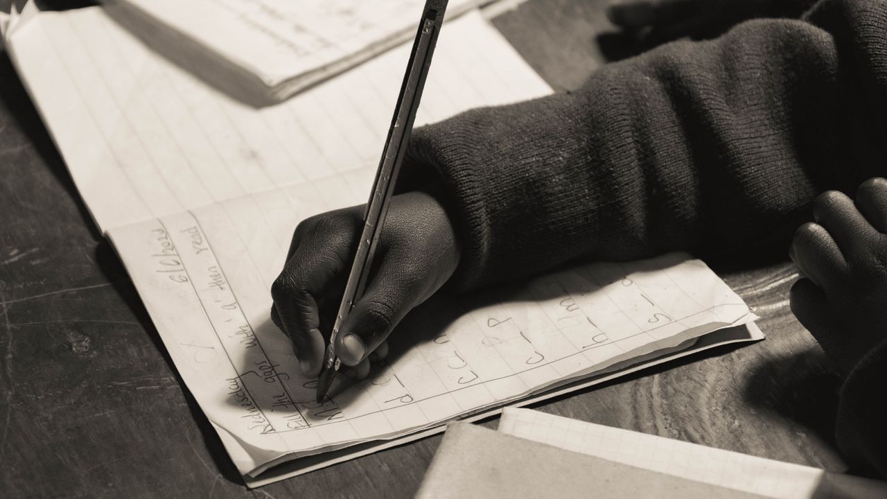 Close-up of a child writing in a notebook, focusing on handwriting practice.