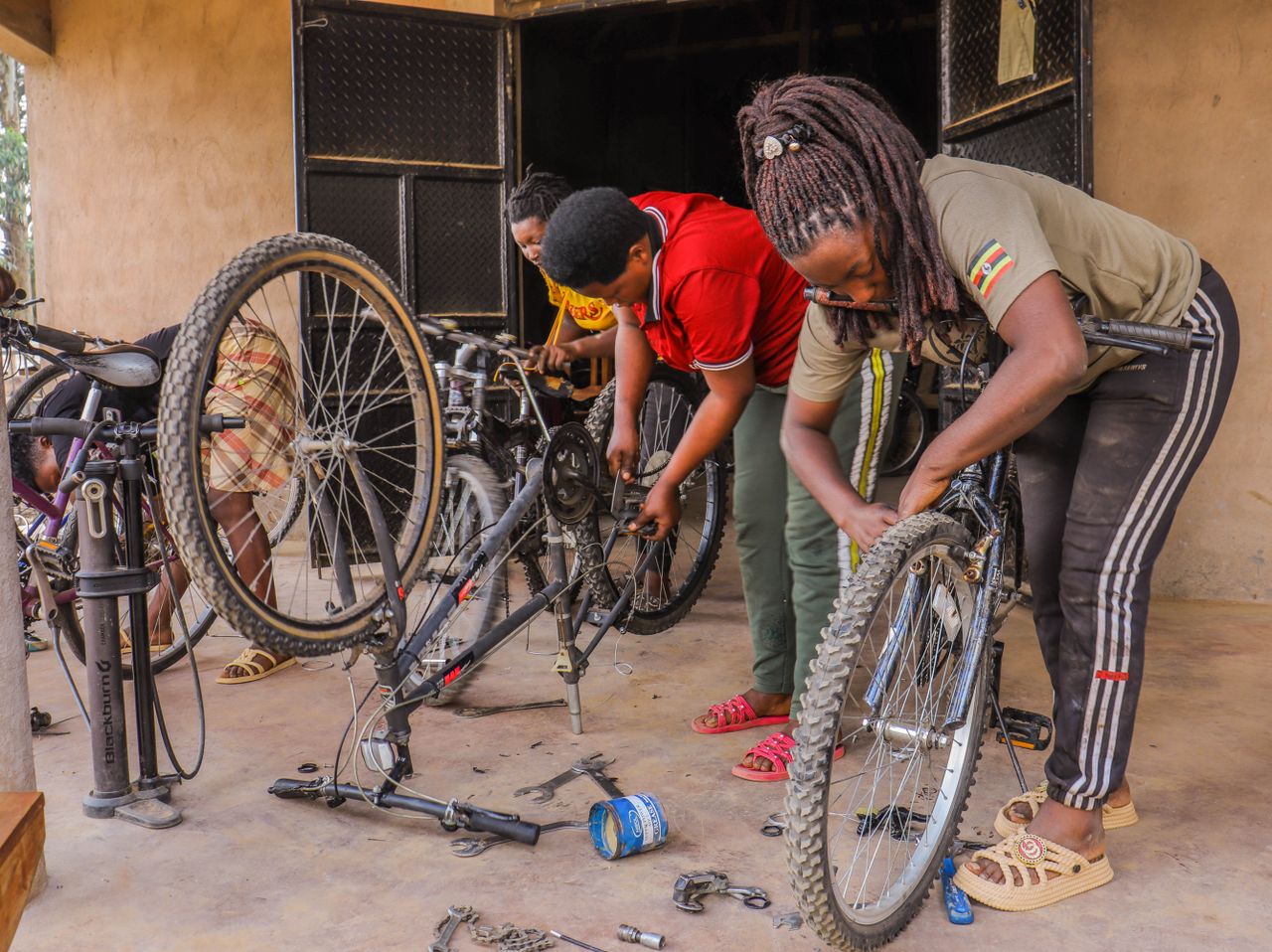 Three women collaboratively repairing bicycles in an indoor workshop.